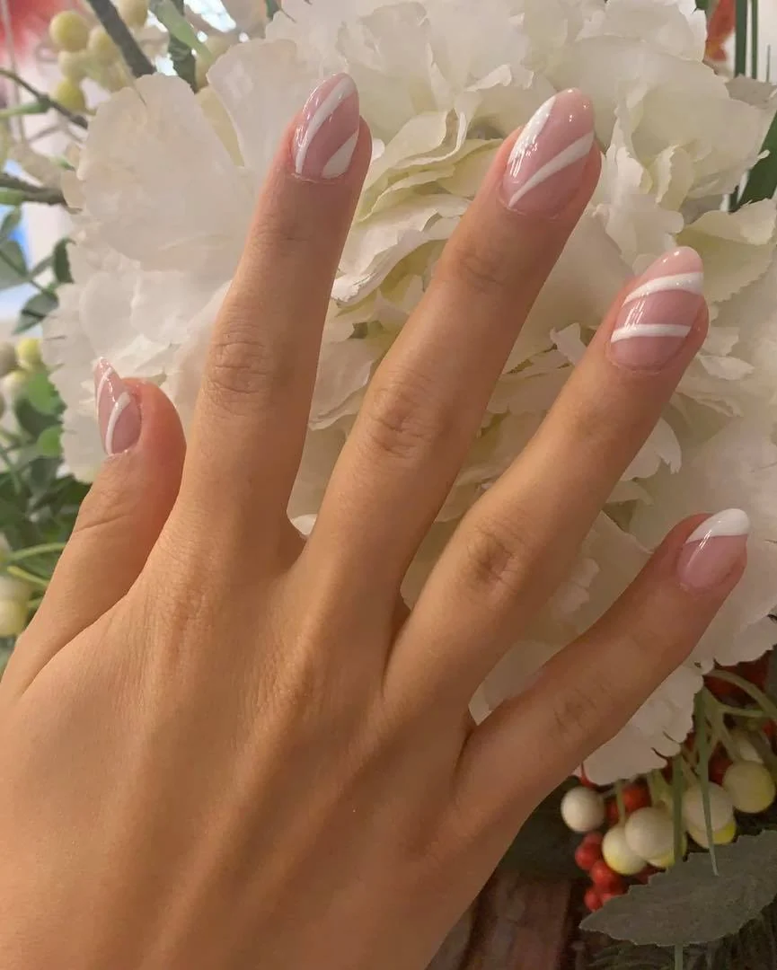 Roséfarbene Nagelmodellage vor Blumen